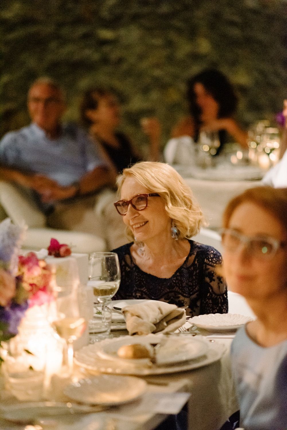 An elegant dinner reception with candlelight and floral centerpieces at a rustic stone venue.