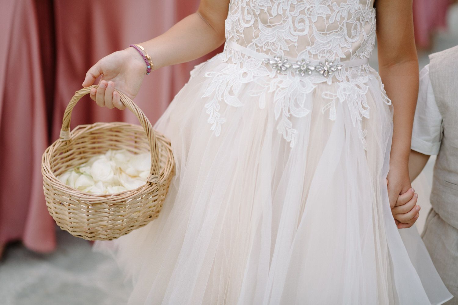 Close-up of delicate lace details and basket on a white wedding dress.