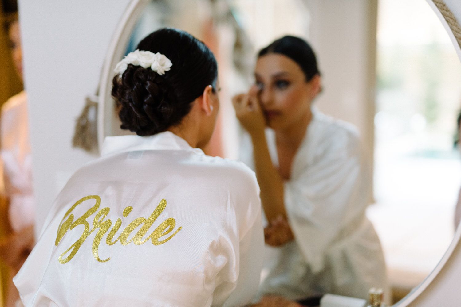 White robe with gold 'Bride' text reflected in vanity mirror.