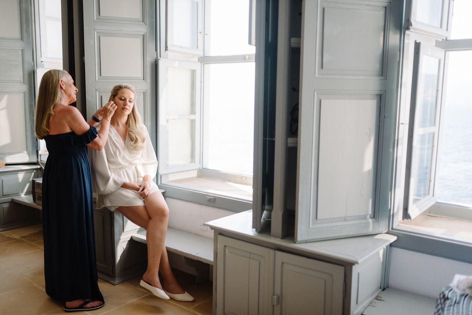 Woman getting earrings adjusted during wedding preparations.