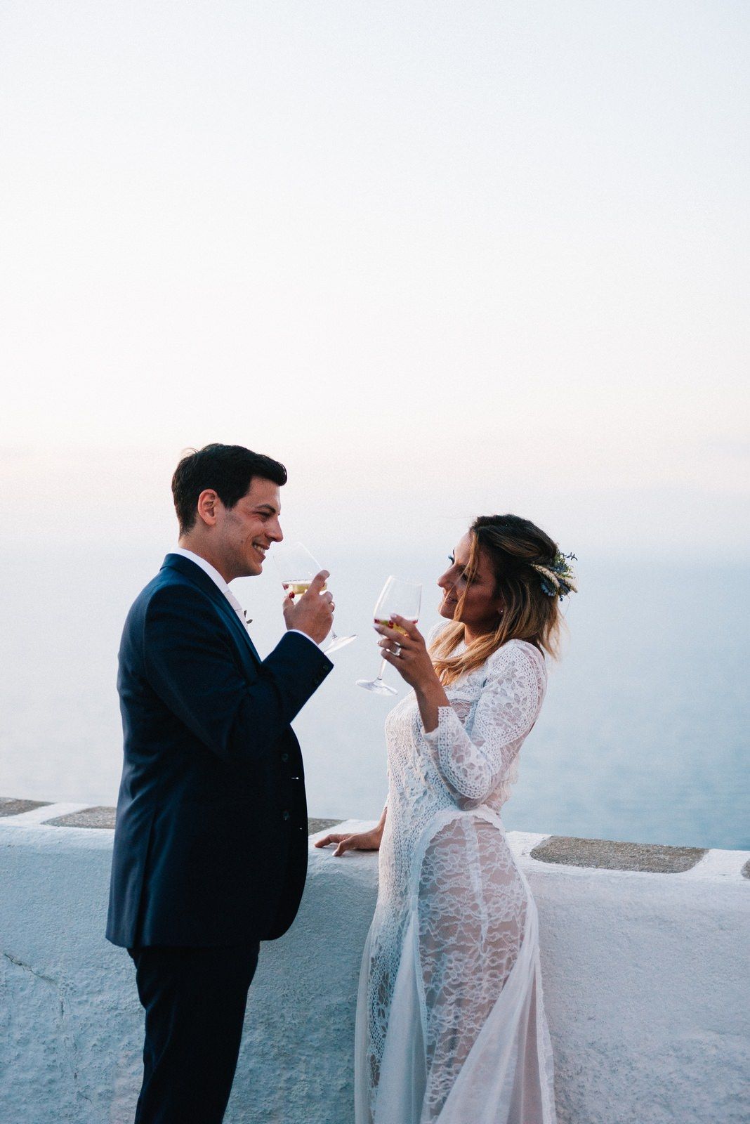 Newlyweds sharing a celebratory toast against a stunning coastal backdrop.
