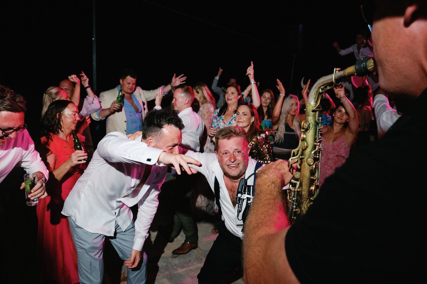 Energetic crowd dancing and celebrating at a lively wedding reception party.