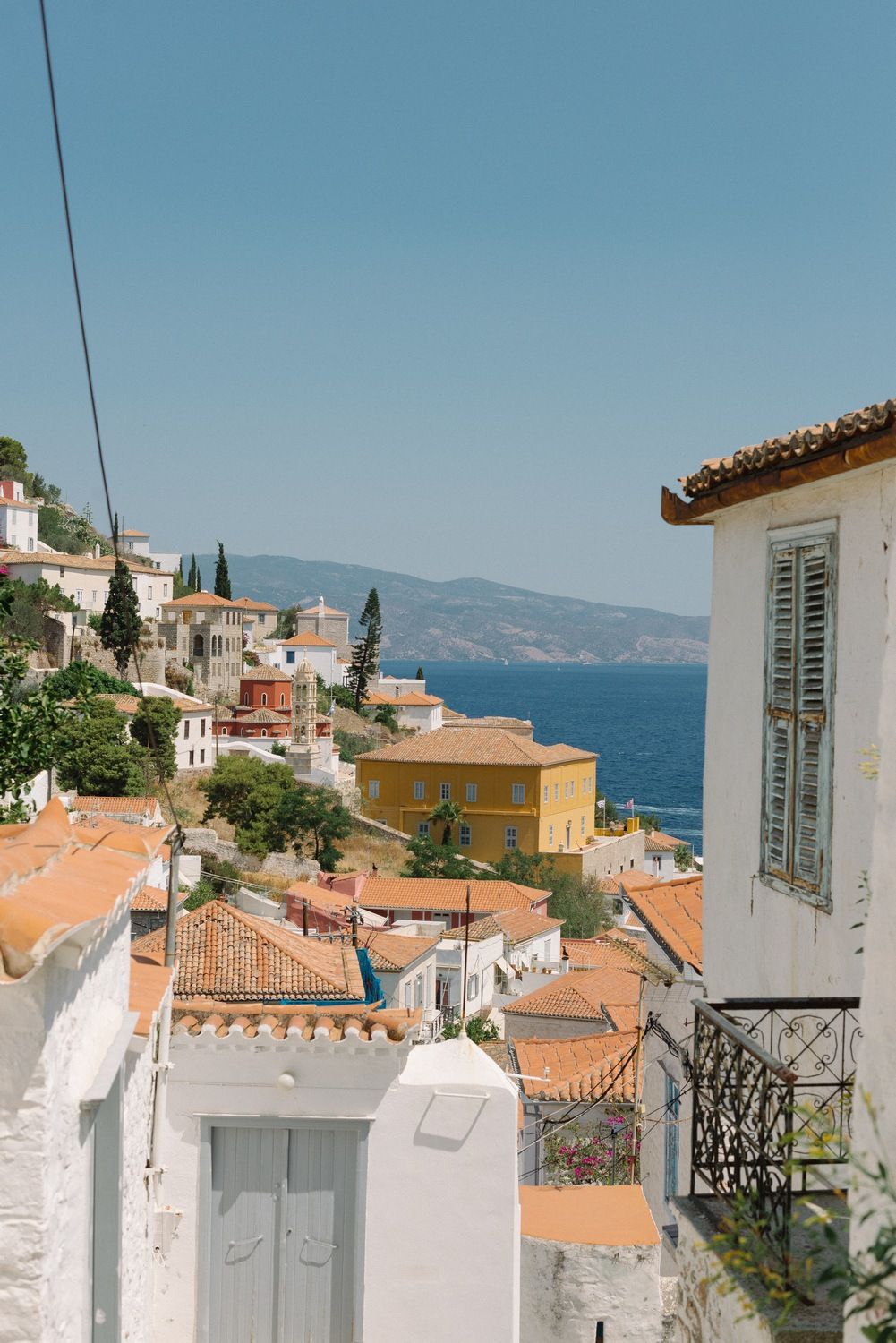 White hillside houses with orange roofs overlooking blue Mediterranean waters.