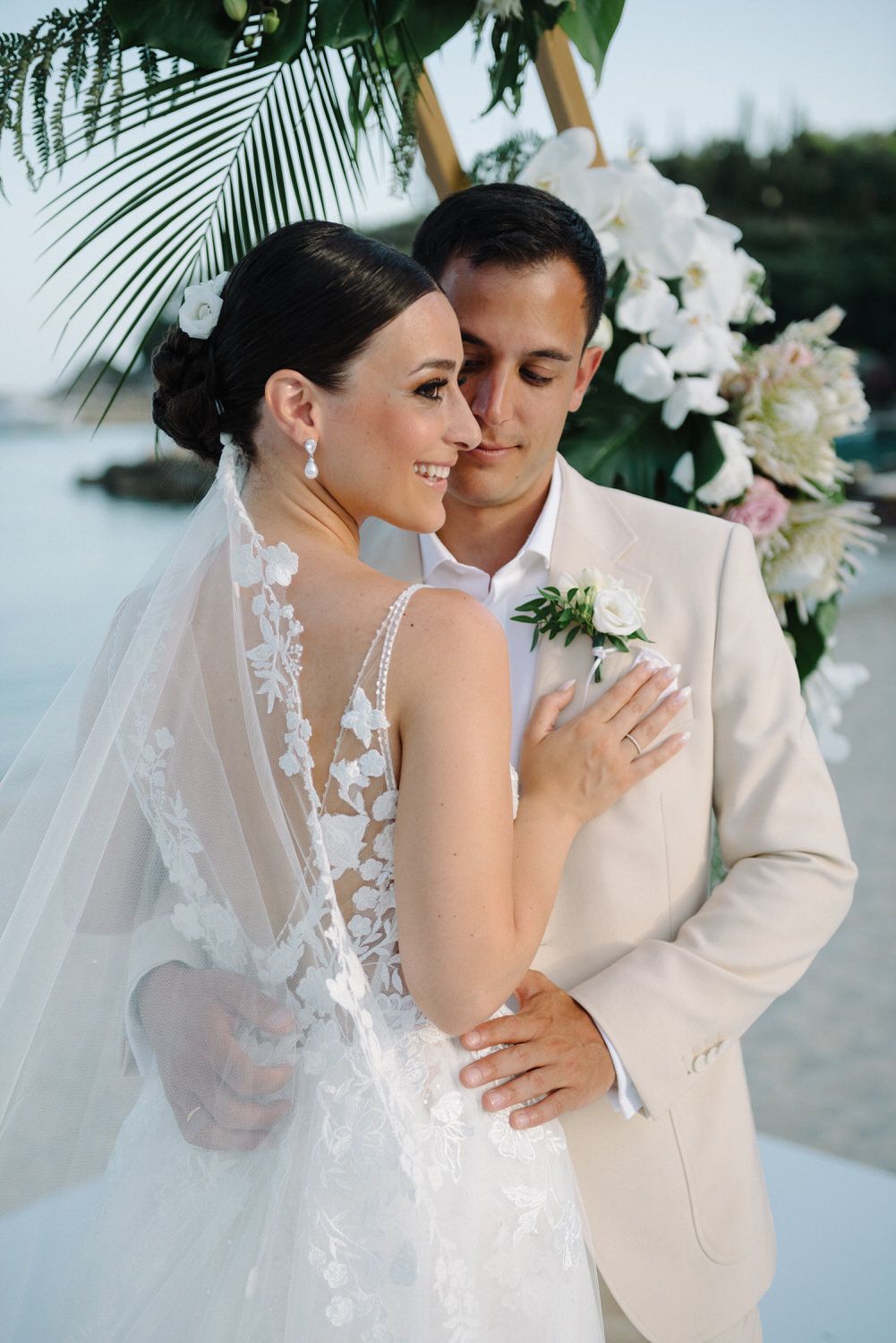 Intimate close-up of couple's embrace showcasing bride's detailed lace wedding dress.