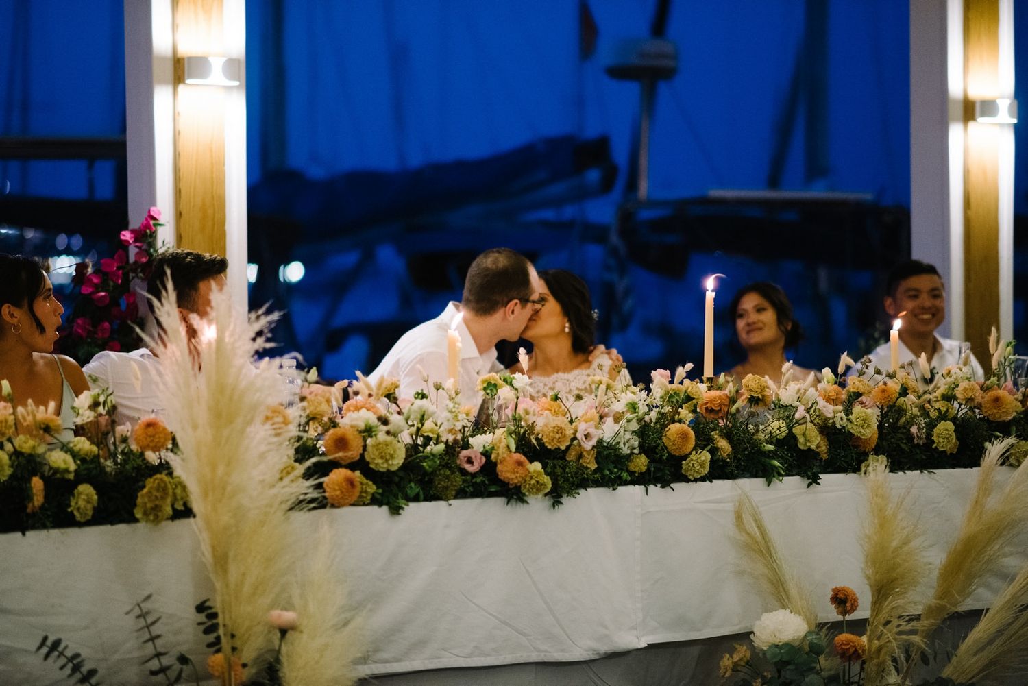 Wedding reception table decorated with lush floral arrangements and pampas grass.