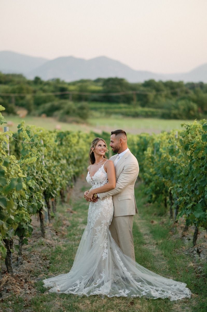 A romantic moment between newlyweds in a vineyard with mountains in the background.
