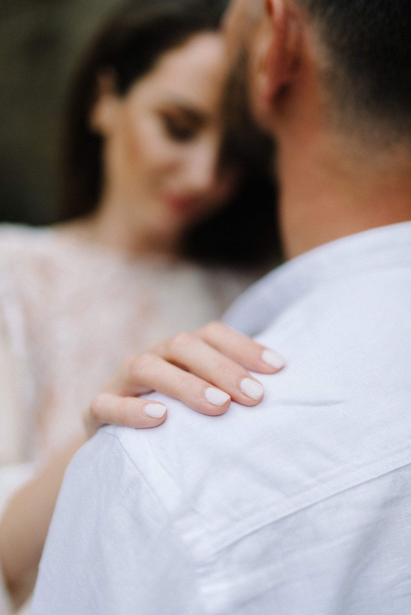 Gentle hand placement on white shirt showing intimate connection.