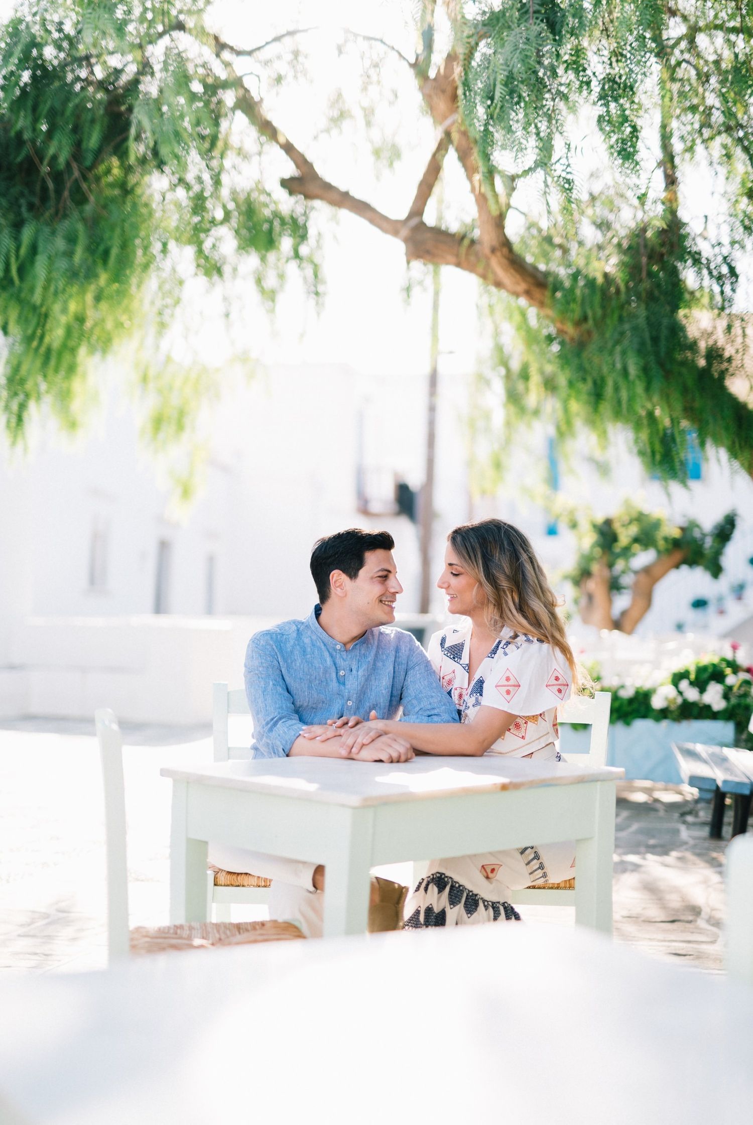 Romantic outdoor dining scene under weeping willow trees in Greece.