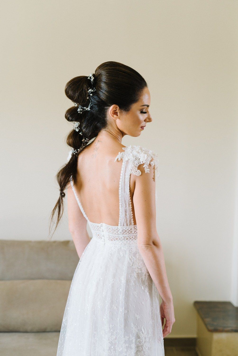 Back view of elegant bridal hairstyle with floral accessories and lace dress detail.