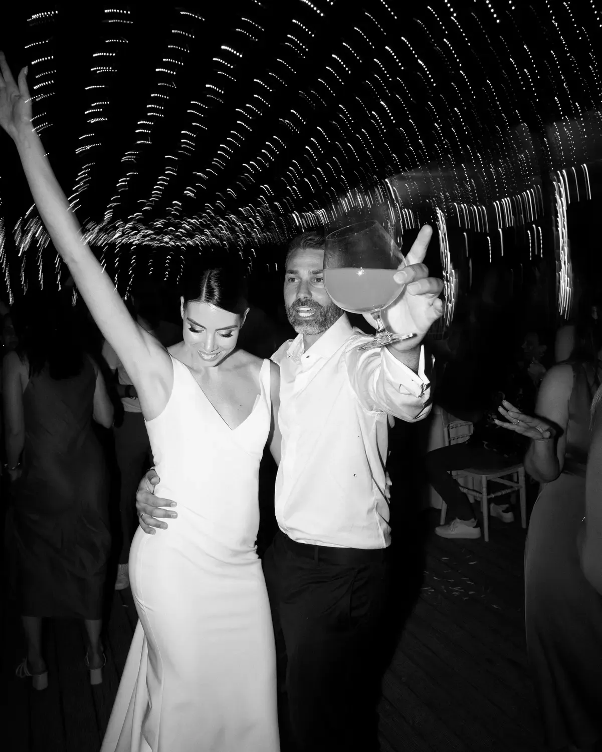 A series of black and white photos showing people dancing and celebrating under a decorative ceiling at a party.