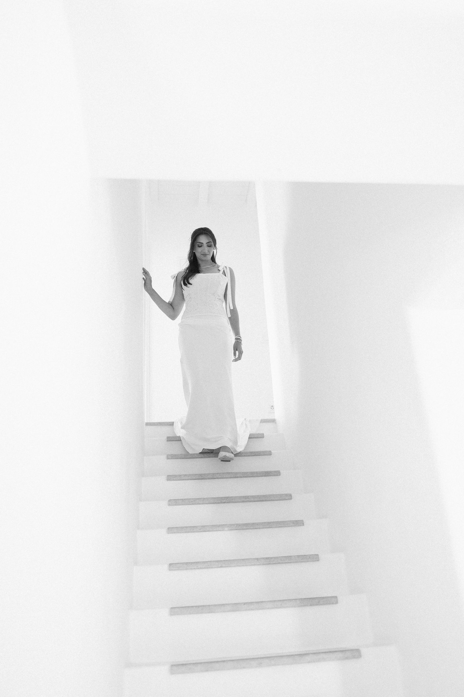 A minimalist sequence showing a bride in white ascending concrete steps in a bright at Mykonos Greece