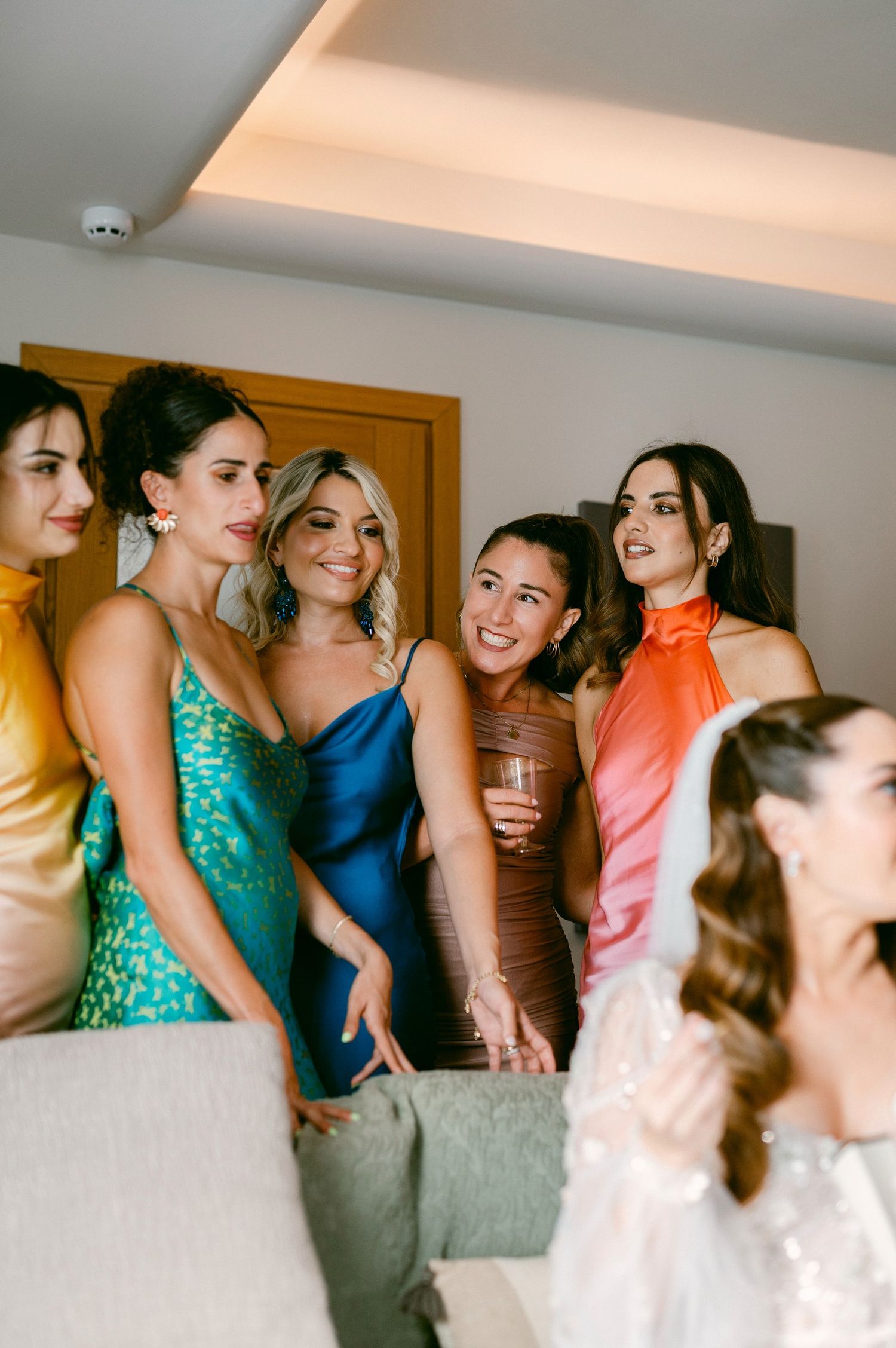 A group of wedding attendees in colorful dresses gather together during a celebration.