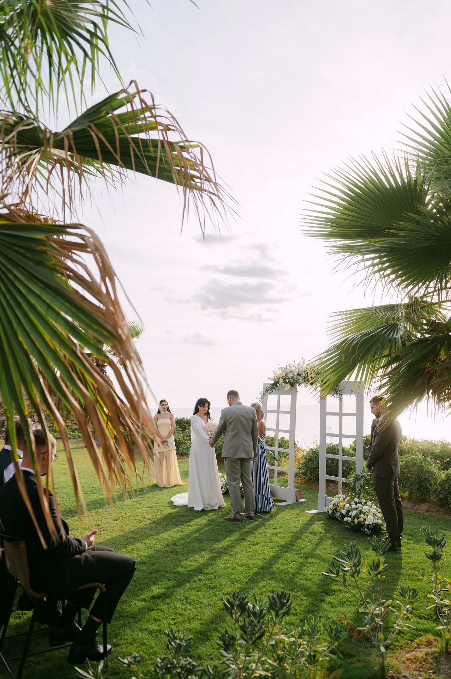 Wedding under swaying palm fronds at a scenic outdoor venue during golden hour.