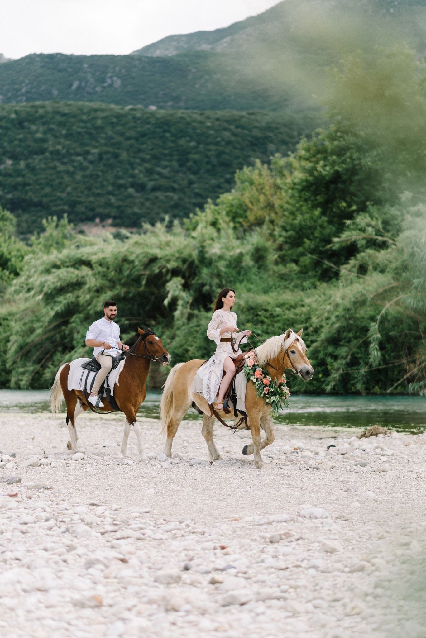 Two riders exploring mountain trails on horseback during a sunny day.