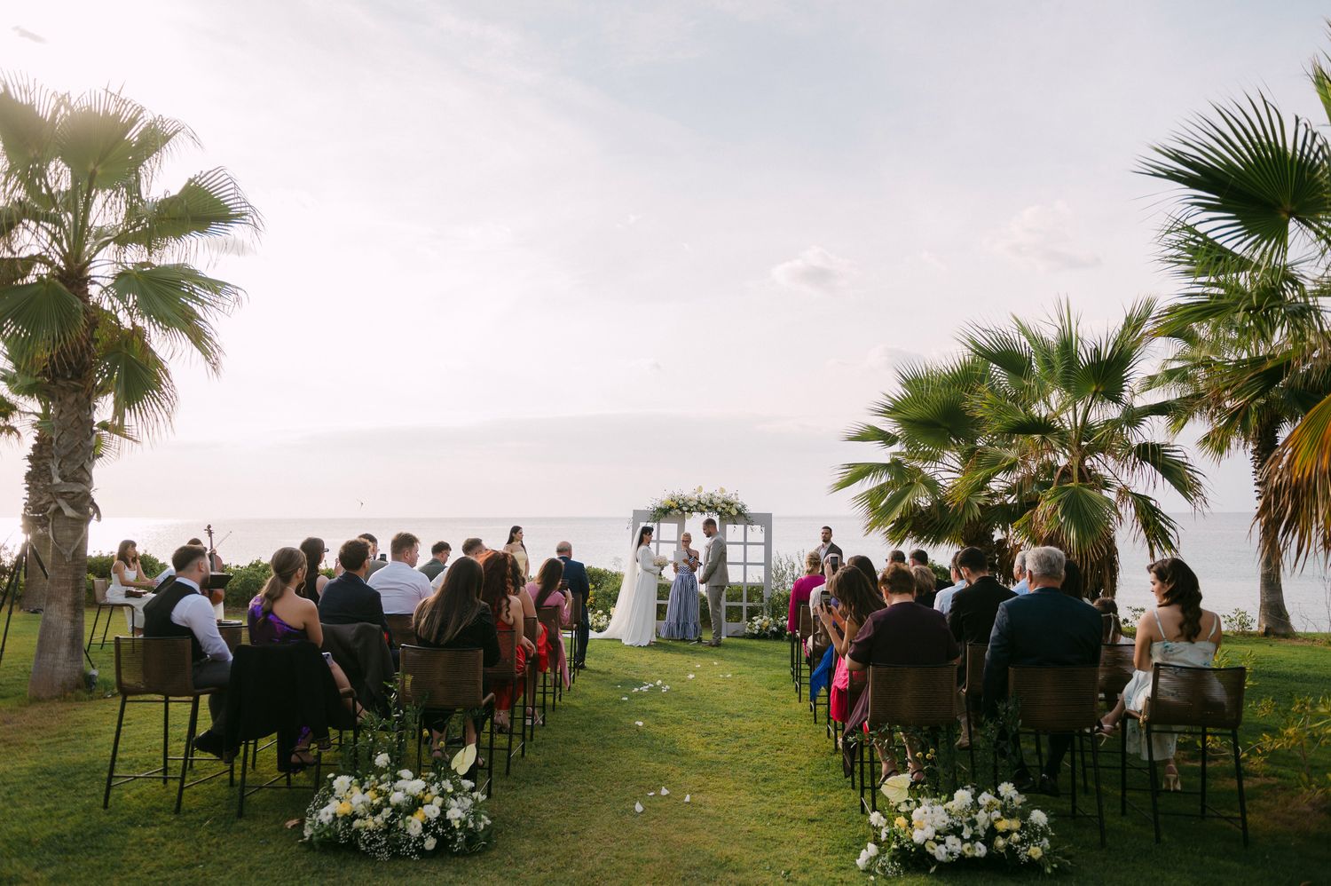 Panoramic view of an outdoor wedding ceremony setup with chairs and palm trees in Halkidiki Greece