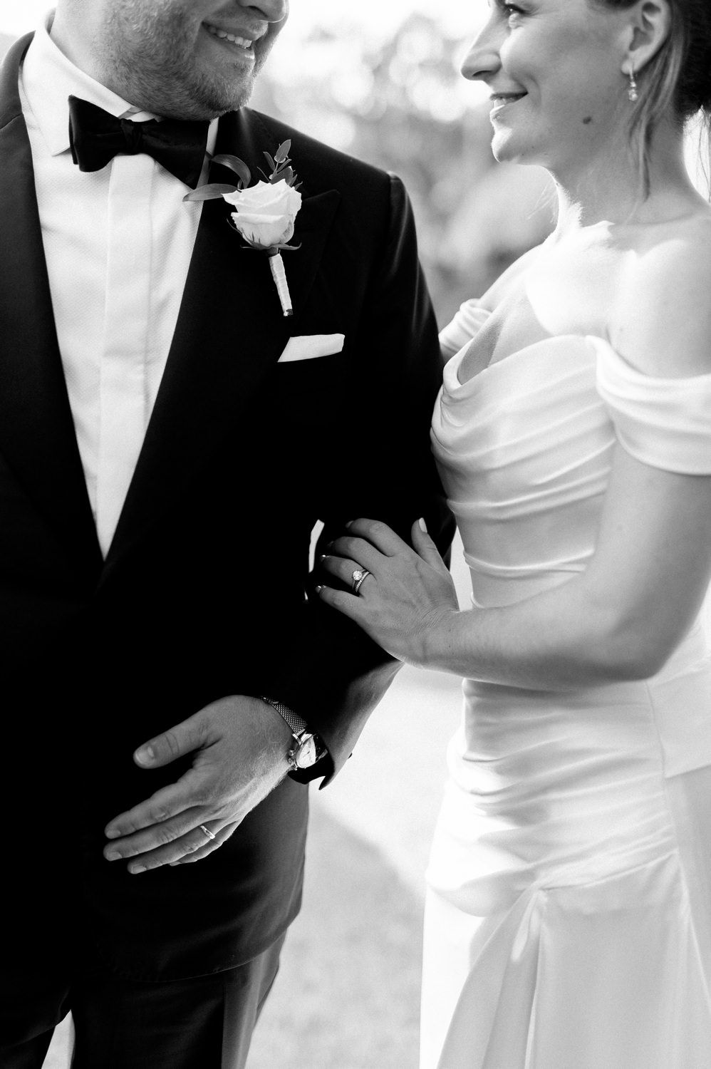 Intimate black and white closeup of newlyweds showing elegant wedding attire details.