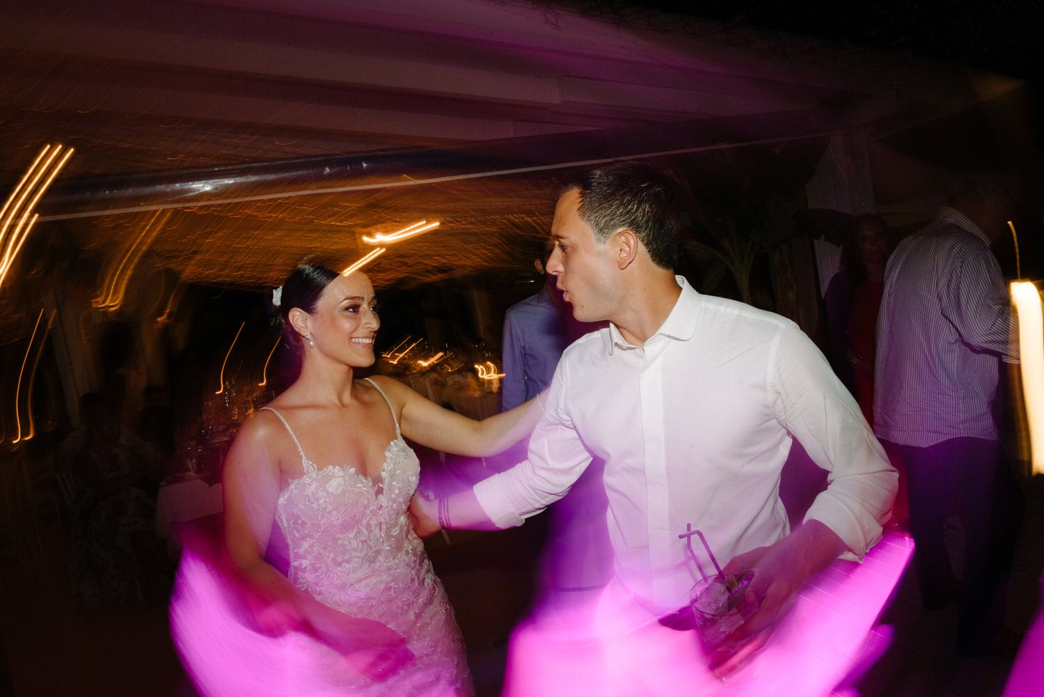 Wedding reception dance floor with pink lighting and energetic dancing.