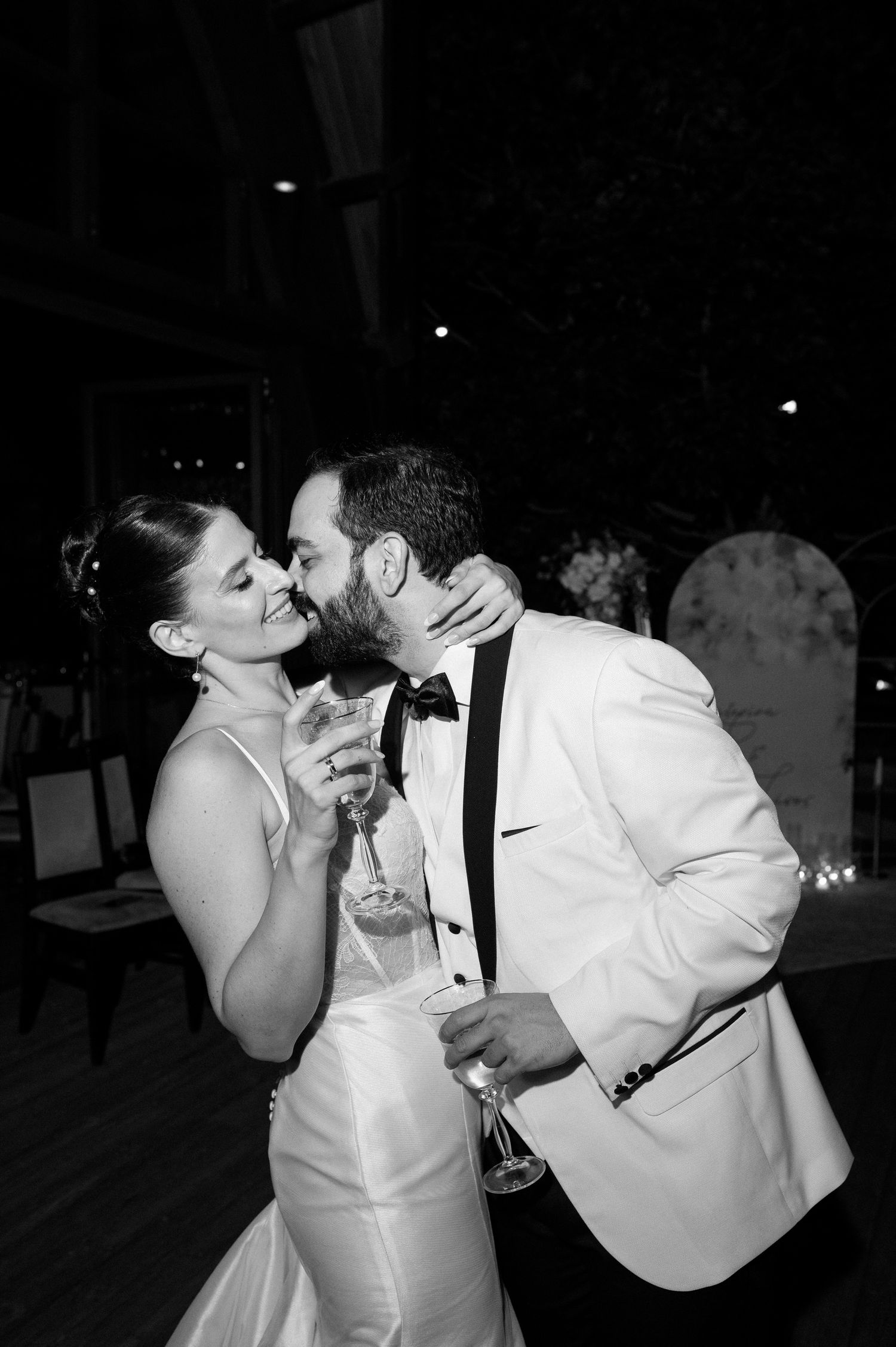 A couple in formal wedding attire share romantic dips and kisses in a series of black and white photos.