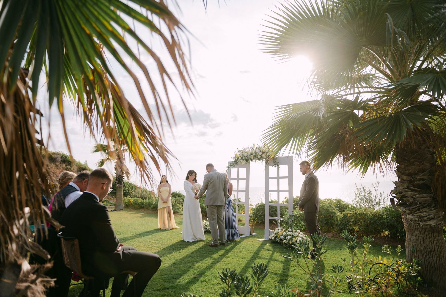 A row of tropical palm trees sways in the breeze along a scenic outdoor pathway at sunset in a wedding in Halkidiki.