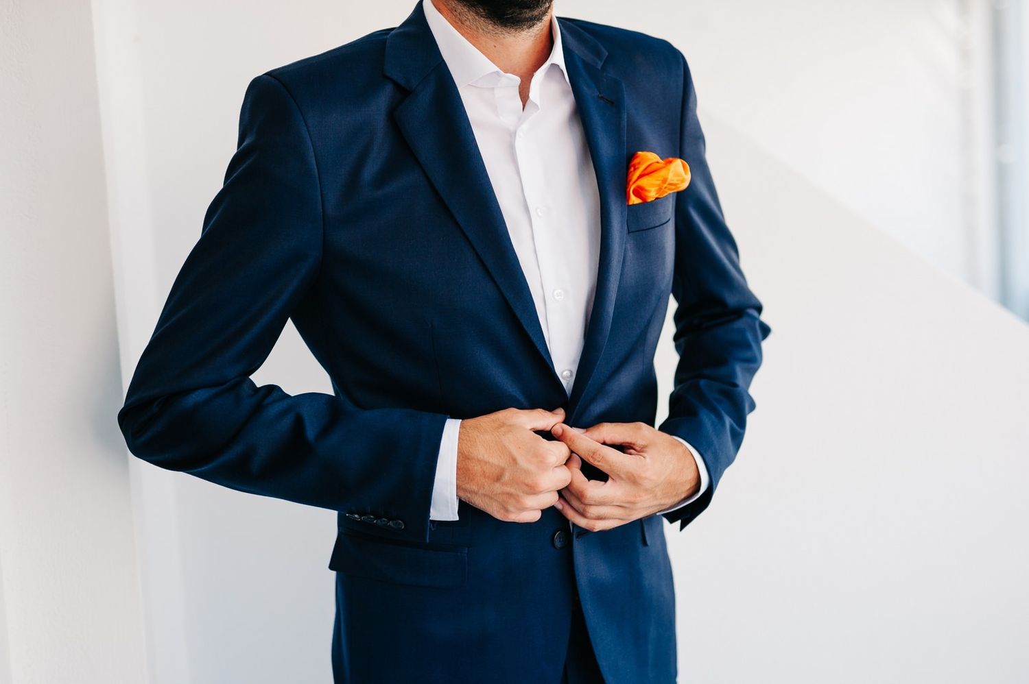 Close-up of navy suit jacket with orange pocket square detail.