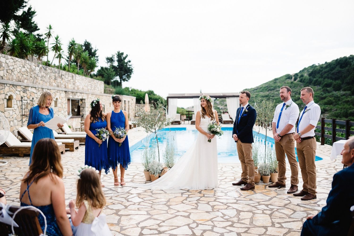 Outdoor wedding ceremony overlooking a pool with stone patio and mountain backdrop.