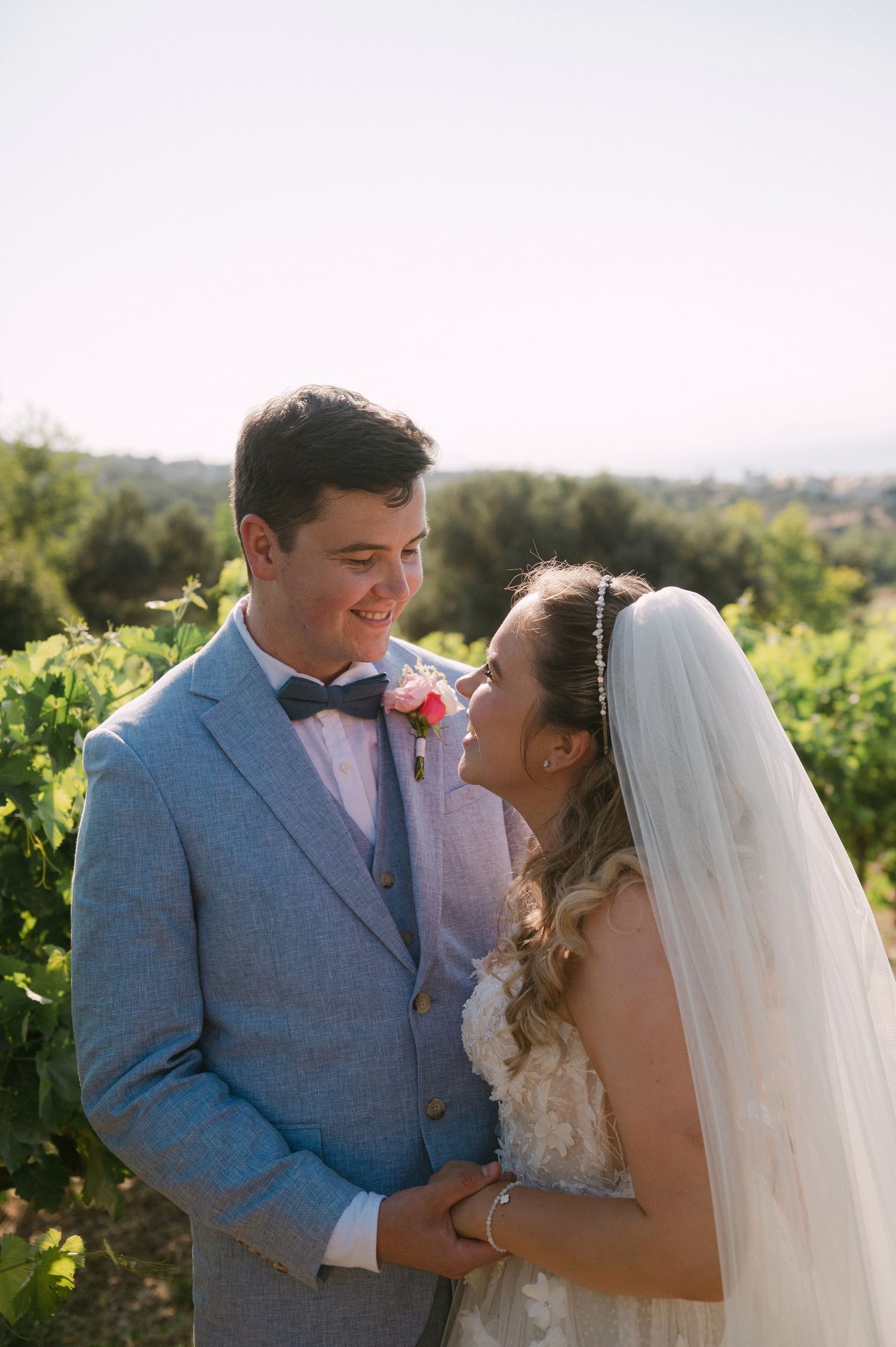Newlywed couple shares intimate moments in a sun-drenched vineyard setting during their wedding photoshoot.