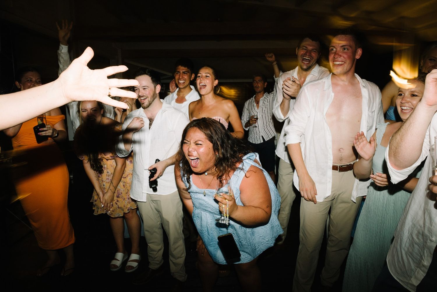 Wedding party guests dancing and celebrating with enthusiasm during a lively reception.