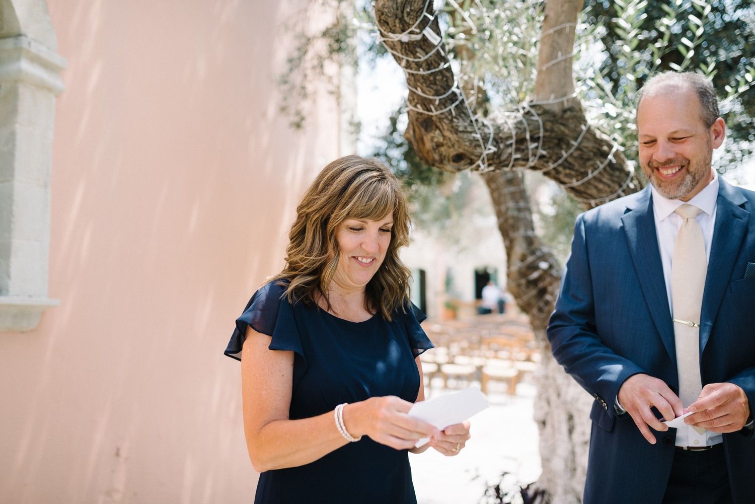Candid moment of people laughing and reading letters at an outdoor wedding venue.