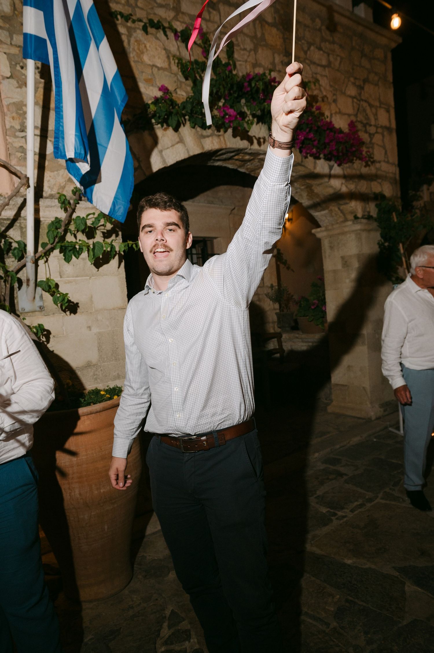 A person dances with enthusiasm at a celebration decorated with blue and white flags.