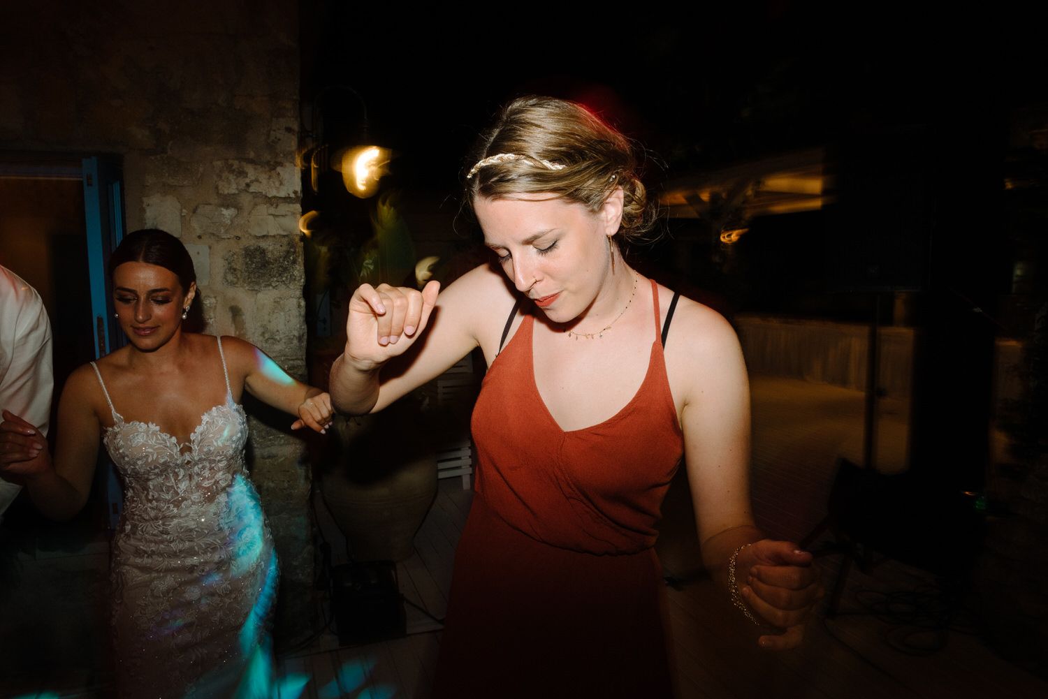 Guests dancing at a dimly lit wedding reception with blue accent lights.