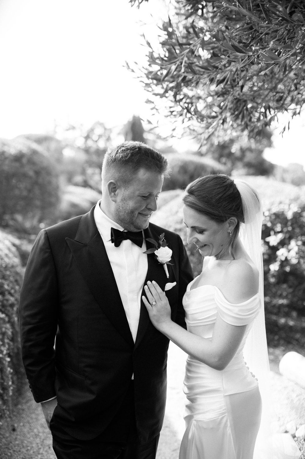Wedding couple shares a tender moment in a garden setting with natural lighting.