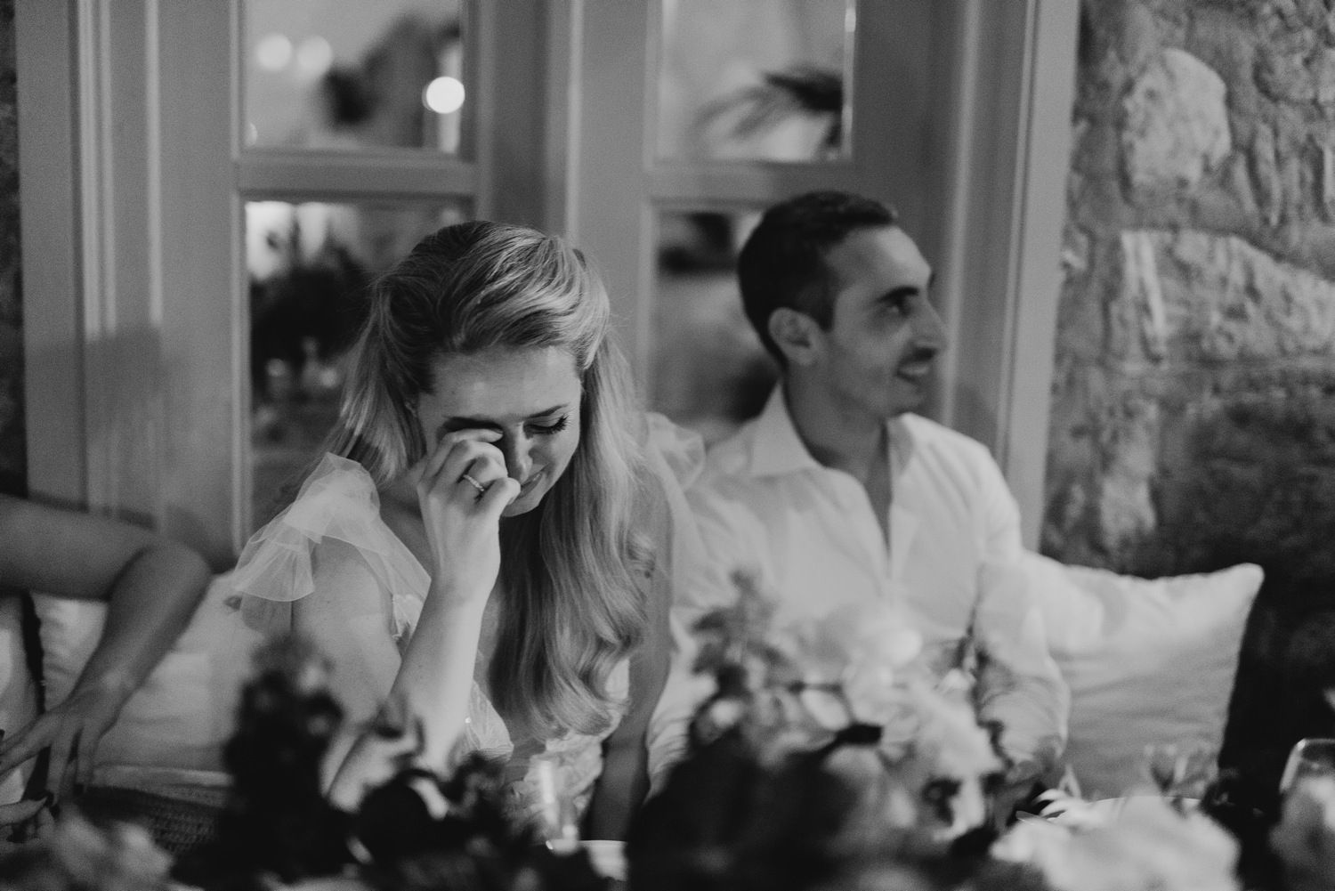 Black and white photo of emotional reactions during wedding reception speeches.