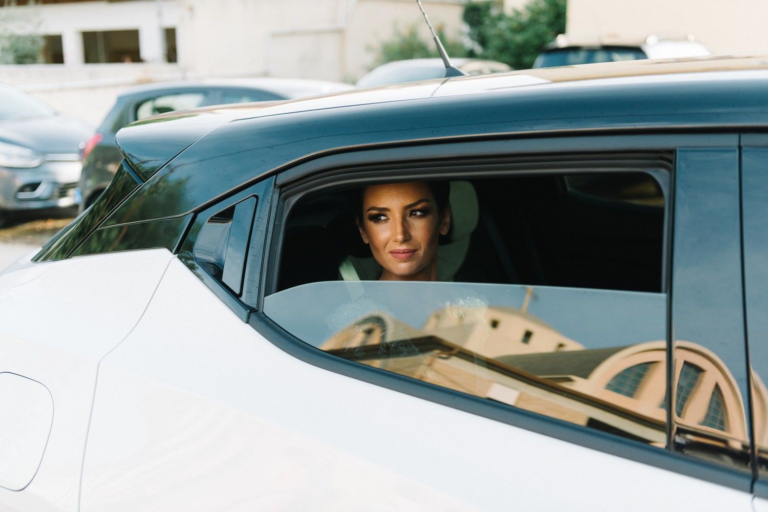 Person in wedding attire seen through car window before ceremony.