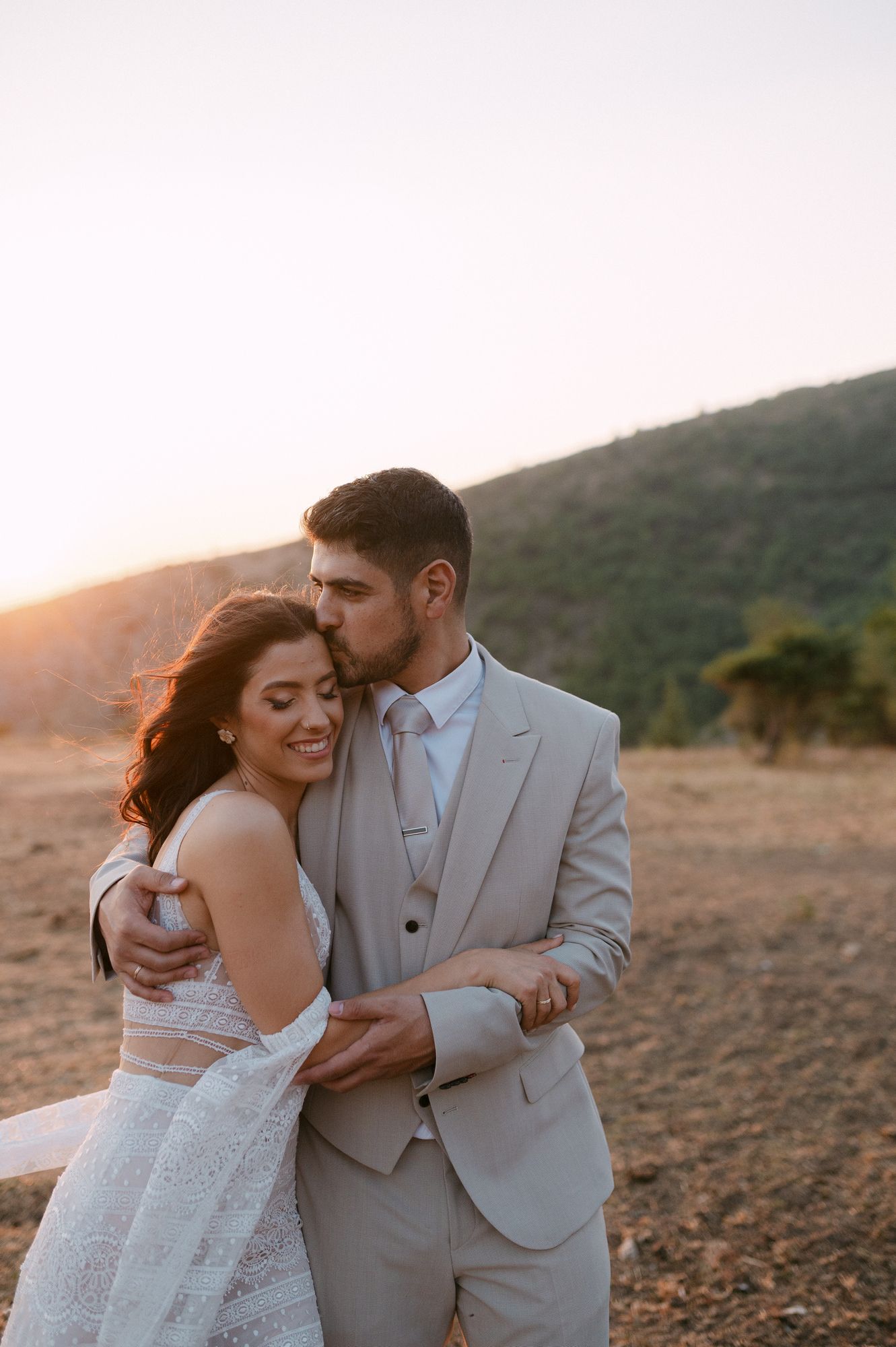Wedding couple shares intimate moments against a mountainous backdrop during sunset photography session.