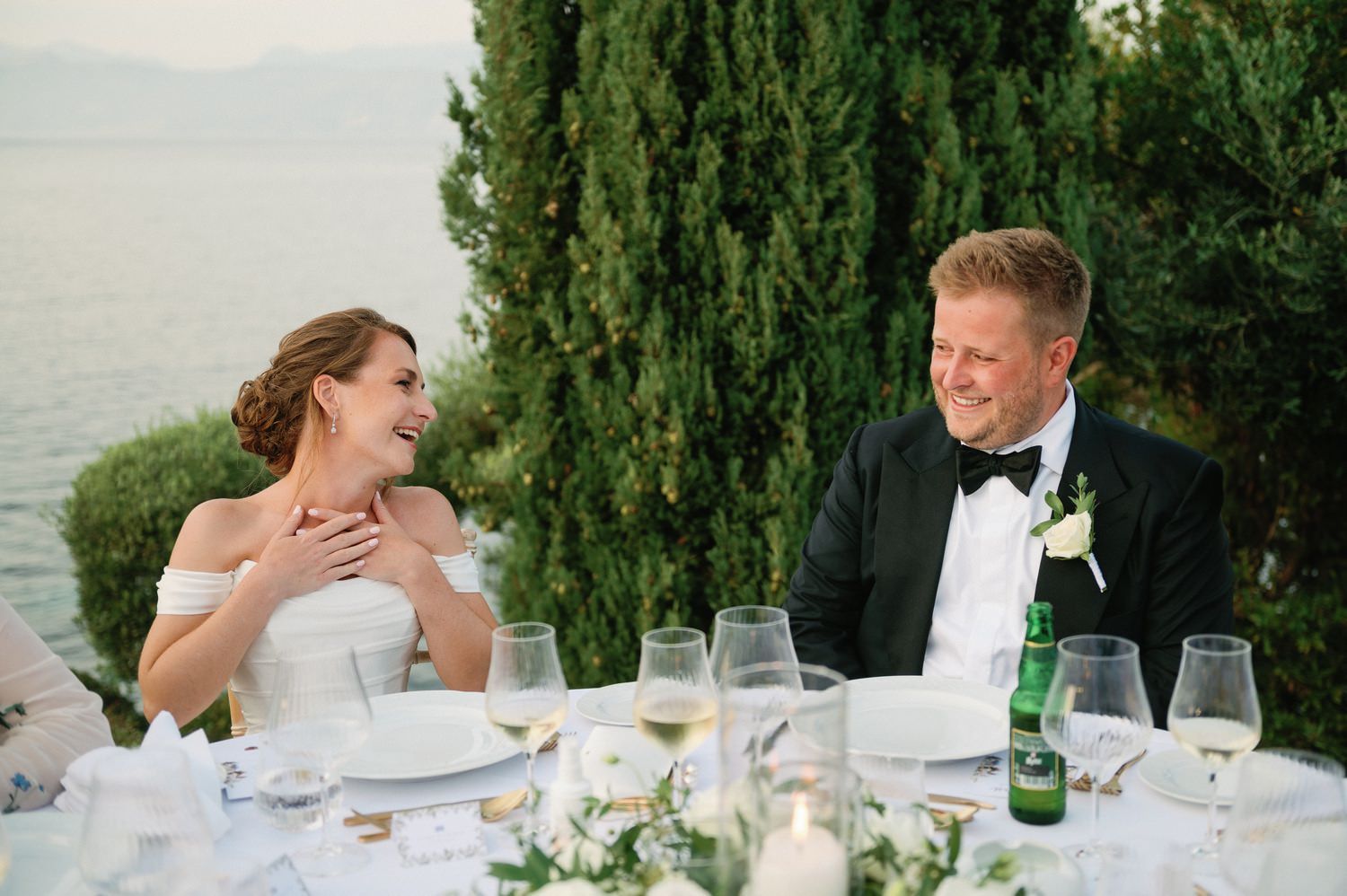 A couple shares a joyful moment during their outdoor wedding reception dinner.