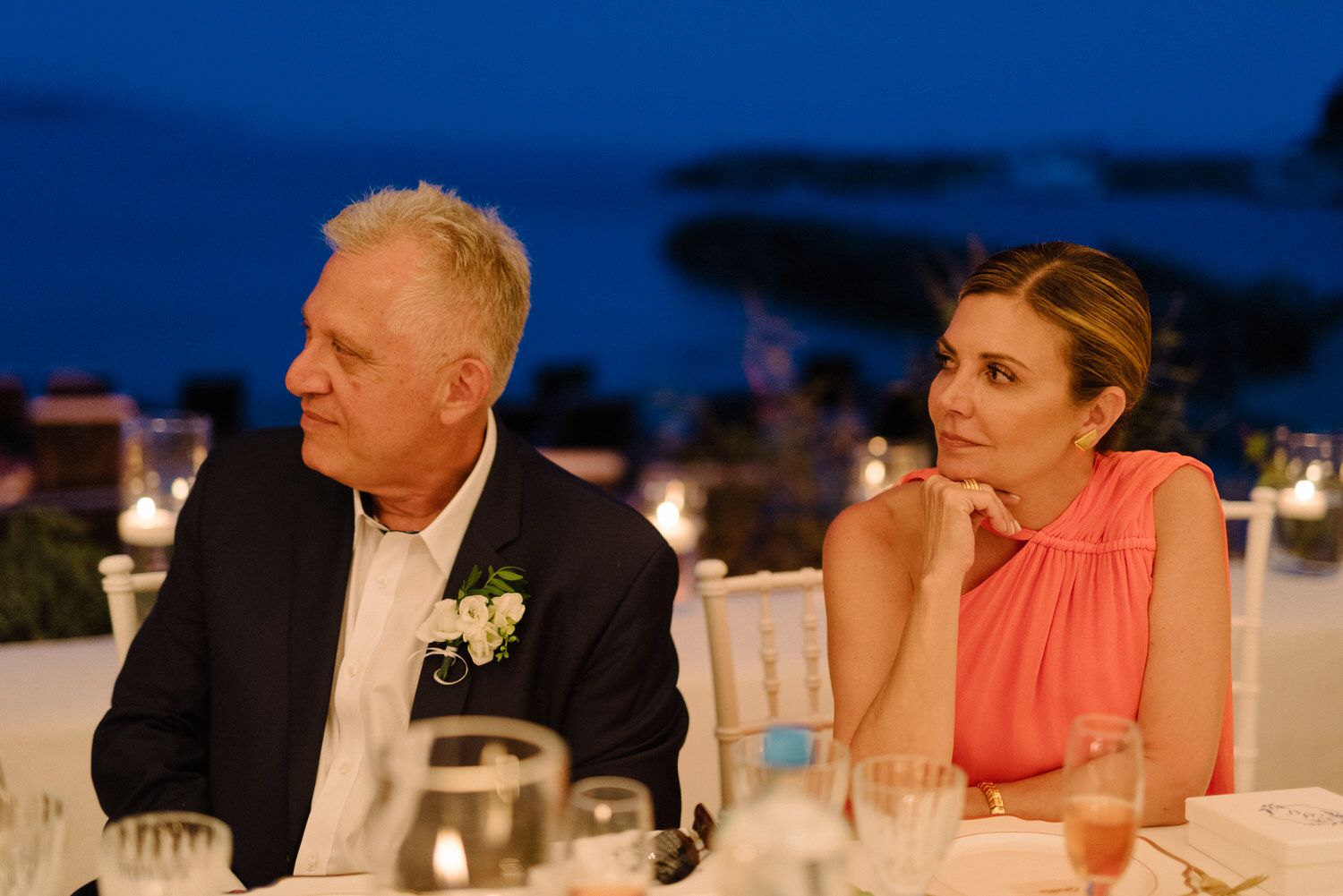 Two guests having a conversation at an elegant outdoor evening wedding reception with ambient lighting.