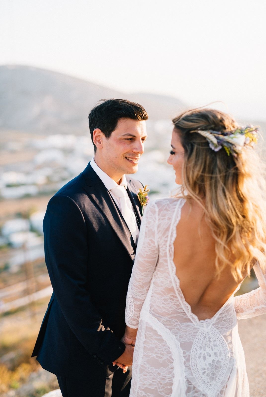 Couple sharing intimate moment against Mediterranean hillside backdrop at sunset.