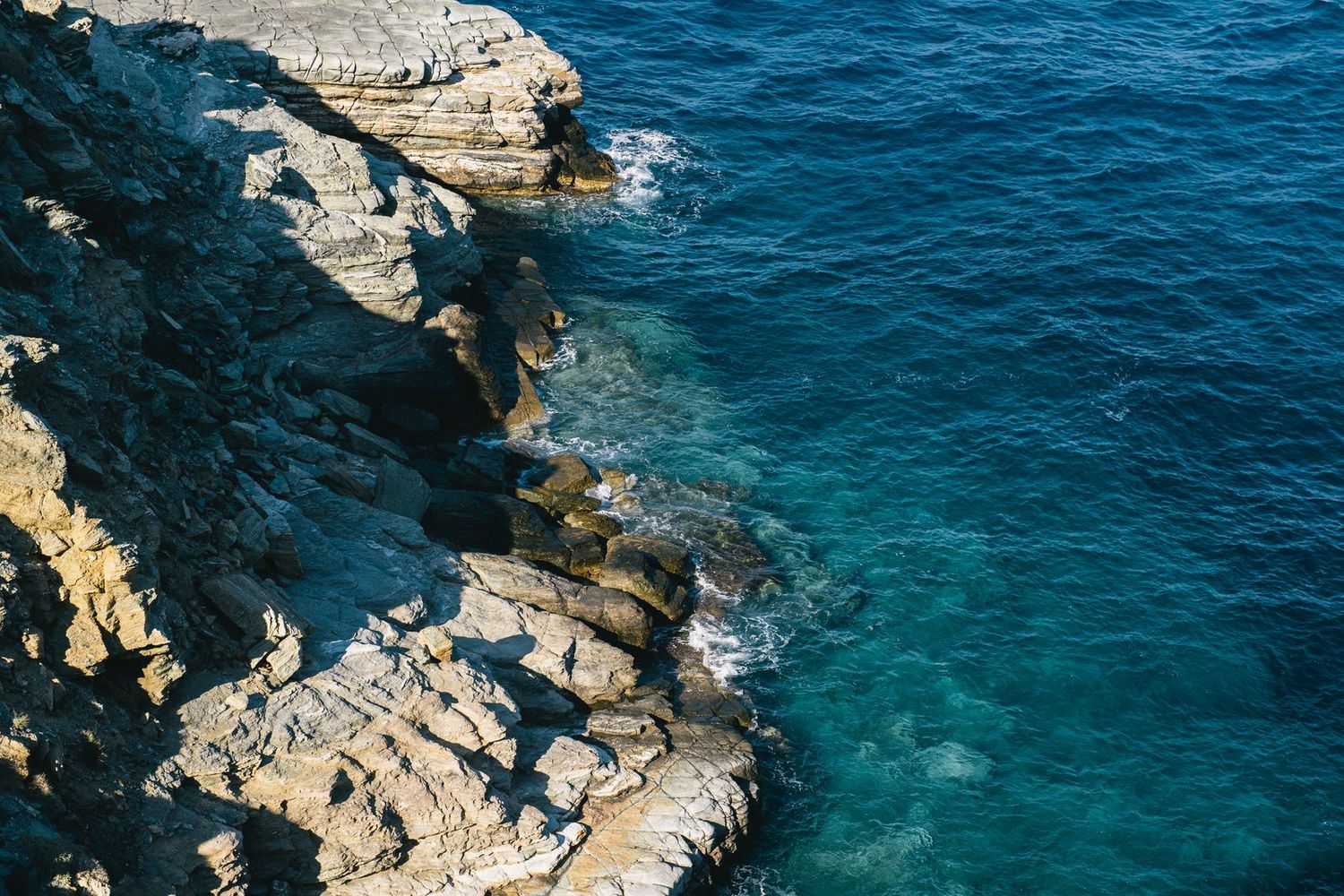 Rocky coastal cliffs meeting crystal clear turquoise Mediterranean waters.