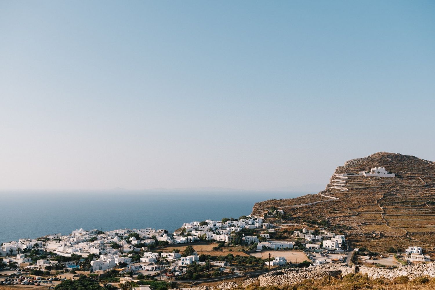 Scenic view of whitewashed buildings nestled on a hillside overlooking the Mediterranean Sea in Greece.