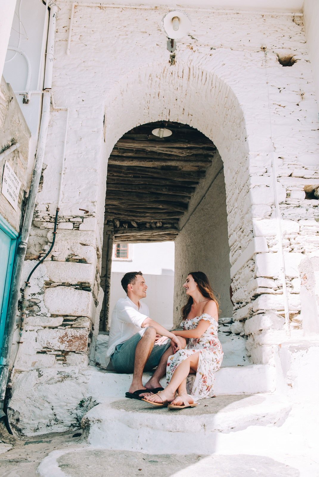 A tender moment shared in a weathered white archway on stone steps in Greece.