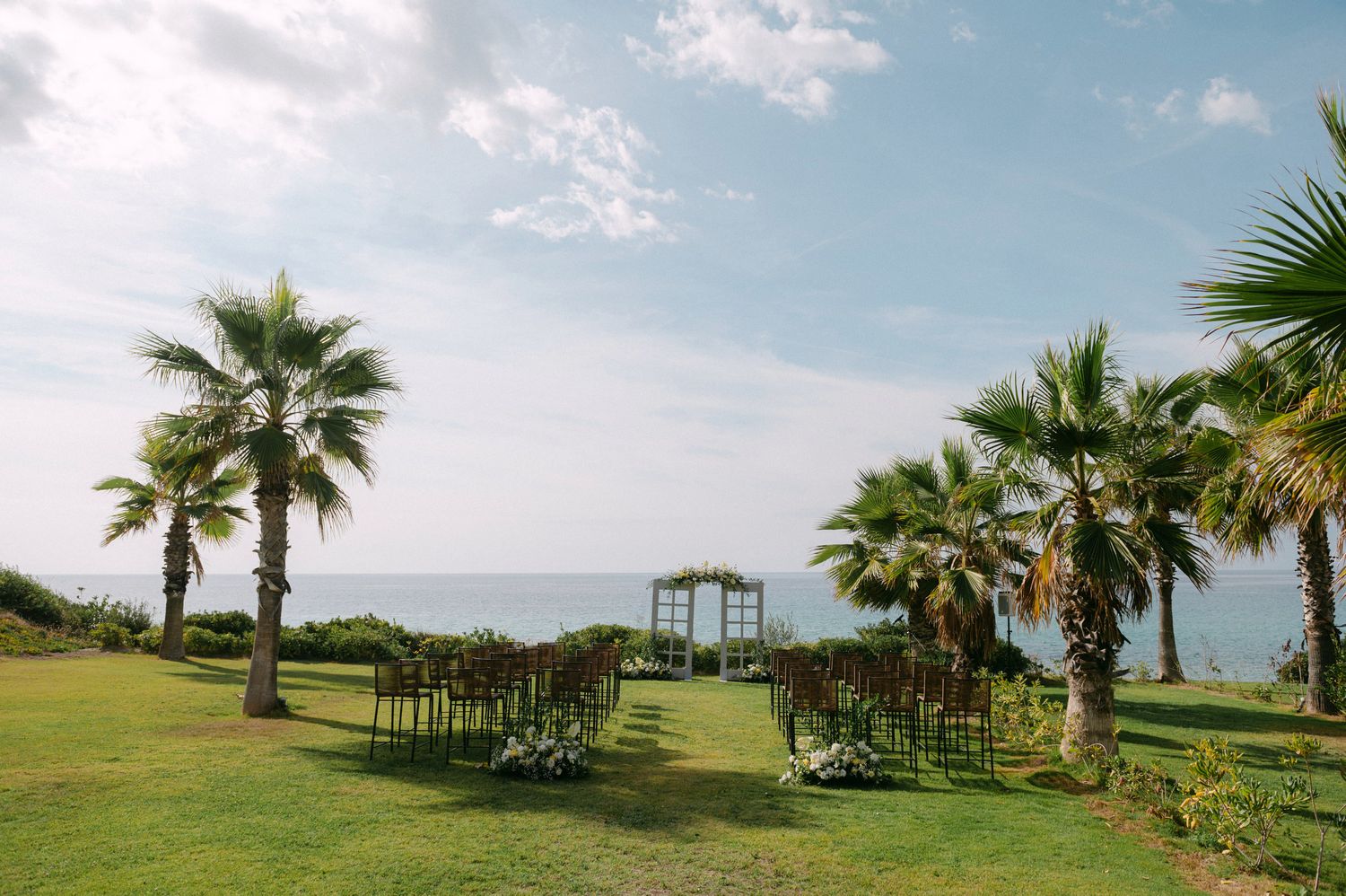 Palm trees line a scenic coastal pathway overlooking sea and mountains at Halkidiki Greece
