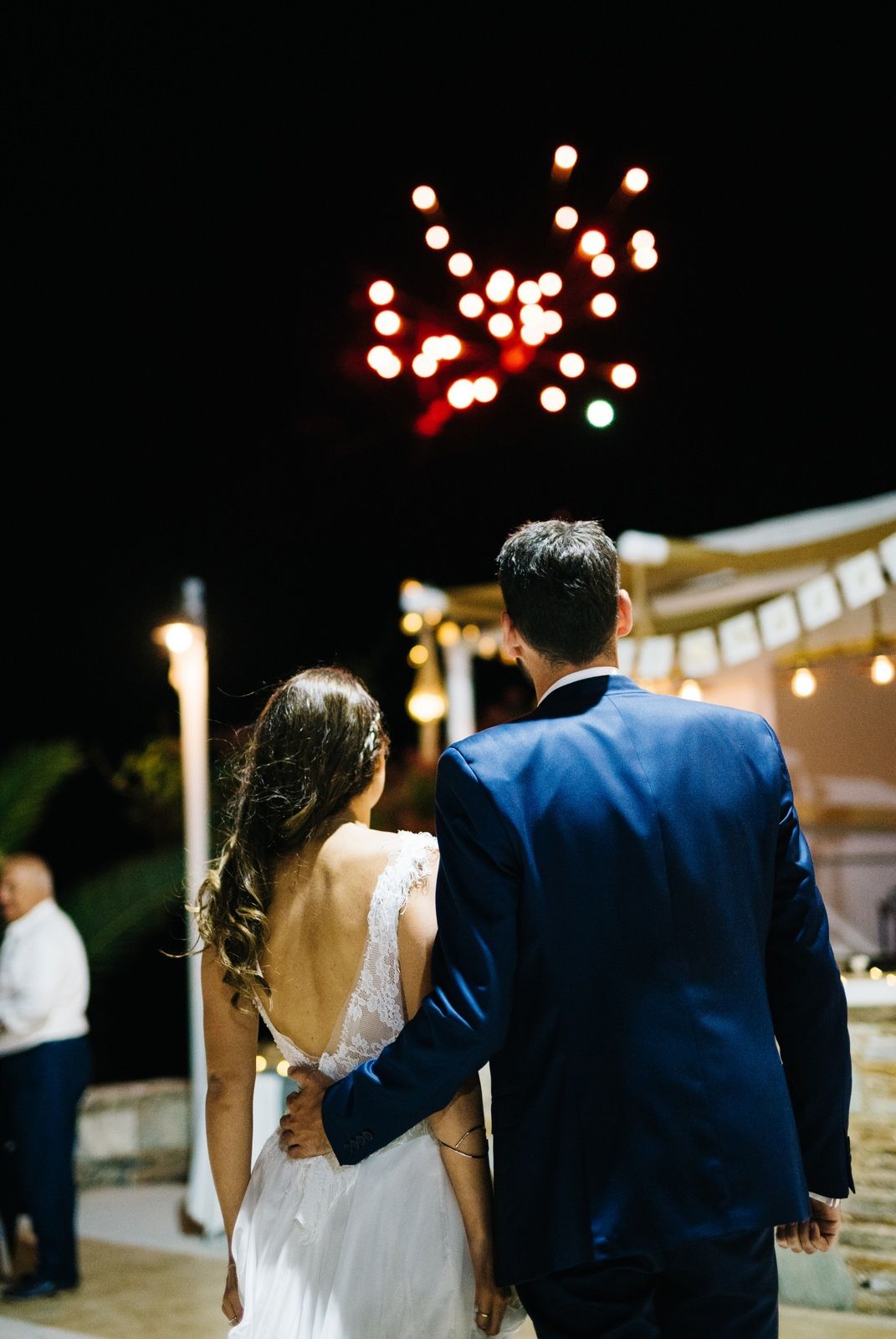 Couple watching fireworks display at nighttime wedding celebration.