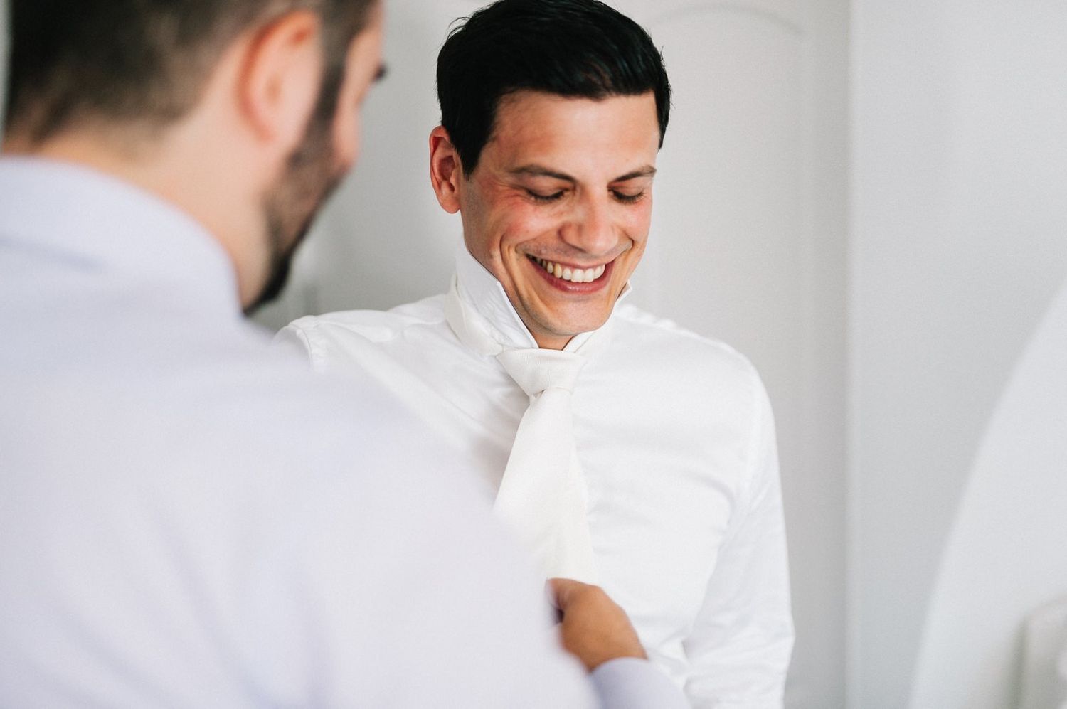 A candid moment captured during formal dressing preparations in a bright interior.