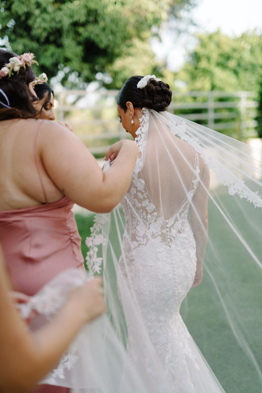 Outdoor wedding photography showing bridesmaids helping with the bride's flowing veil.
