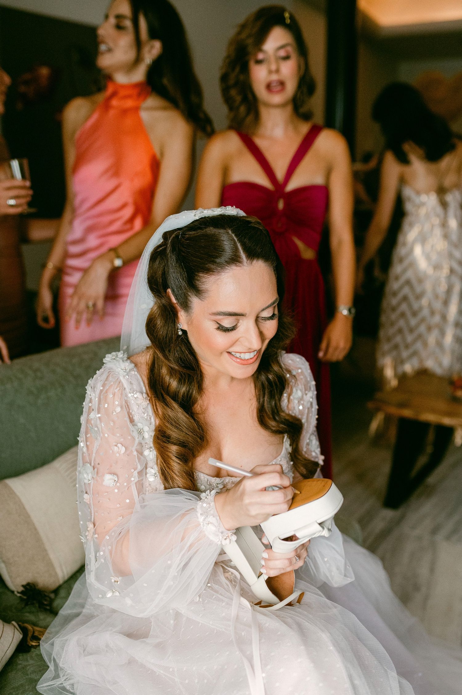 Bride in lace wedding dress smiles while eating snack during wedding reception party.