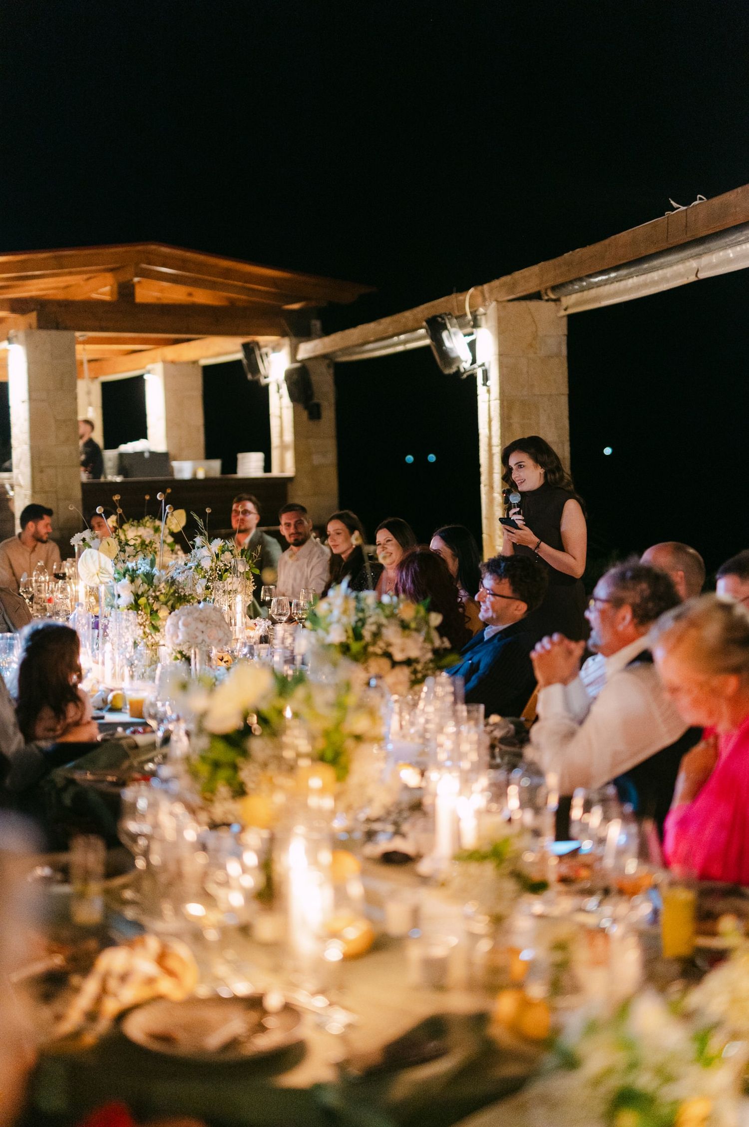 Candlelit wedding reception tables decorated with flowers and glowing centerpieces create an intimate evening atmosphere.