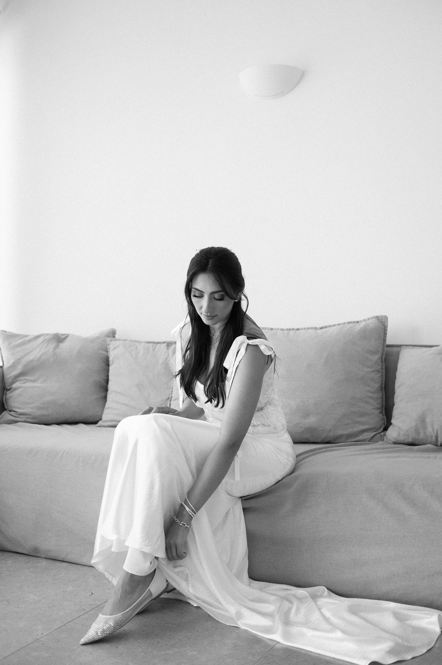 A series of black and white photographs showing a person in a white dress reclining on a light-colored sofa.