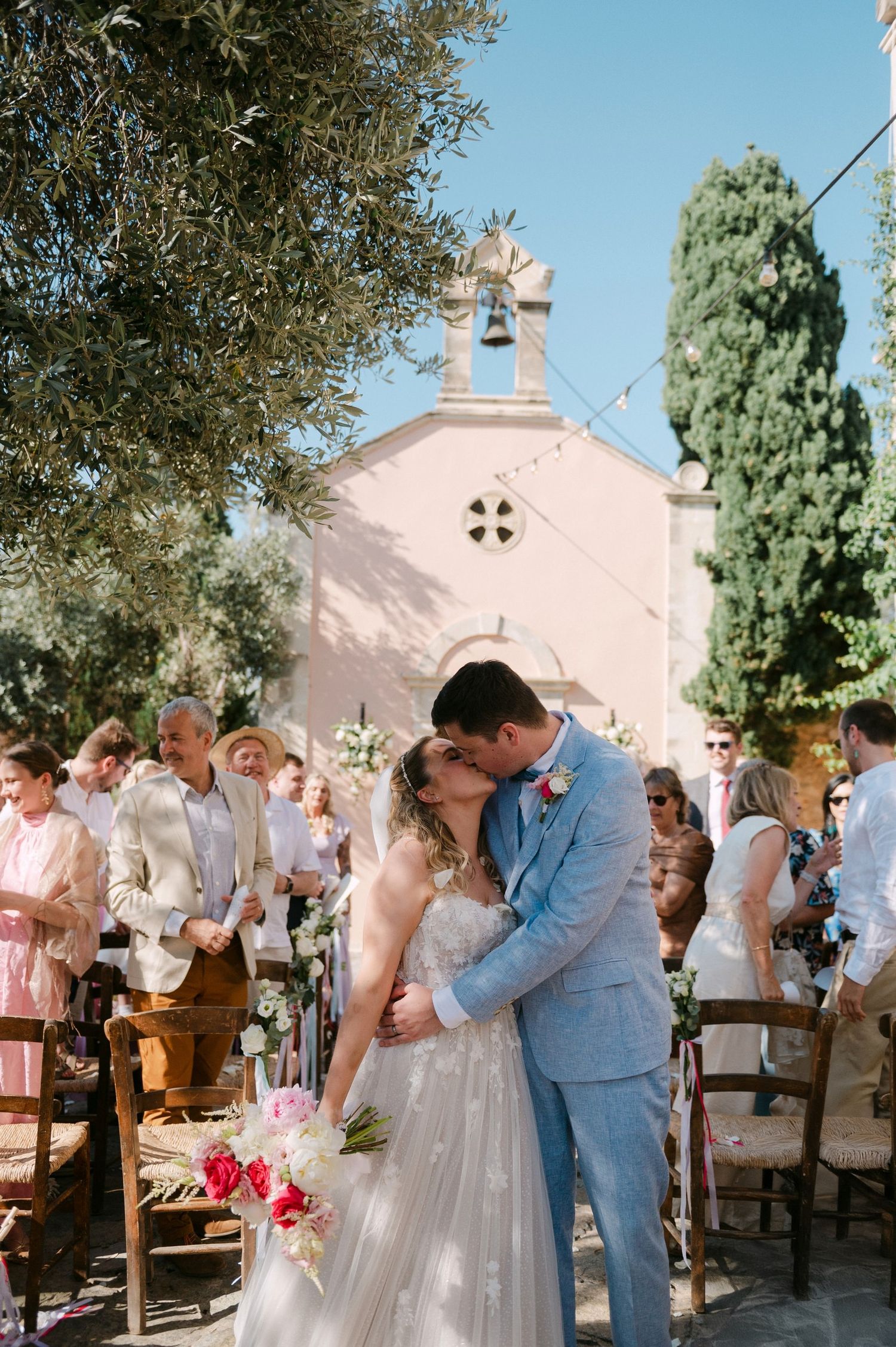 Four candid romantic moments captured of a wedding couple sharing kisses outside a rustic white-walled church.
