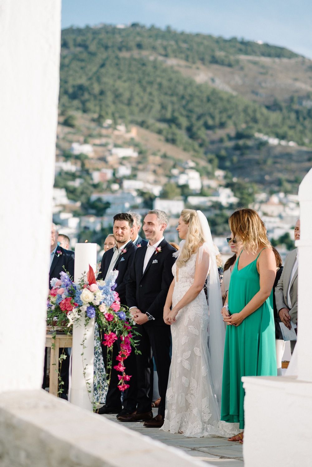 Wedding party standing at the ceremony site with hillside town views in the background.