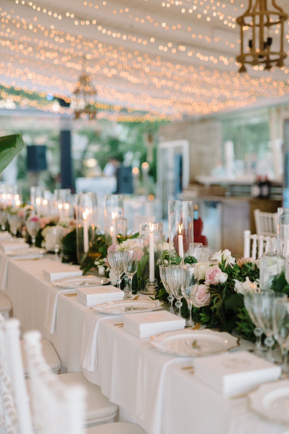 Wedding reception venue with twinkling string lights and elegant white table settings.